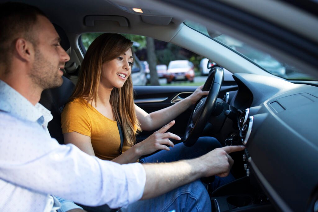 driving instructor showing vehicle dashboard and buttons to the student taking driving lessons. driving instructor showing vehicle dashboard and buttons to the student taking driving lessons.